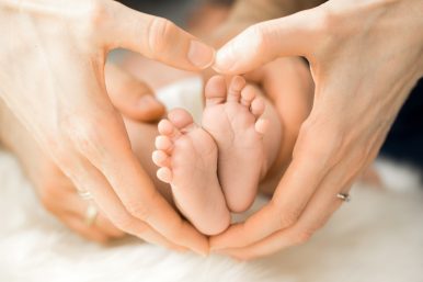 Hand formt ein Herz um Baby Füße